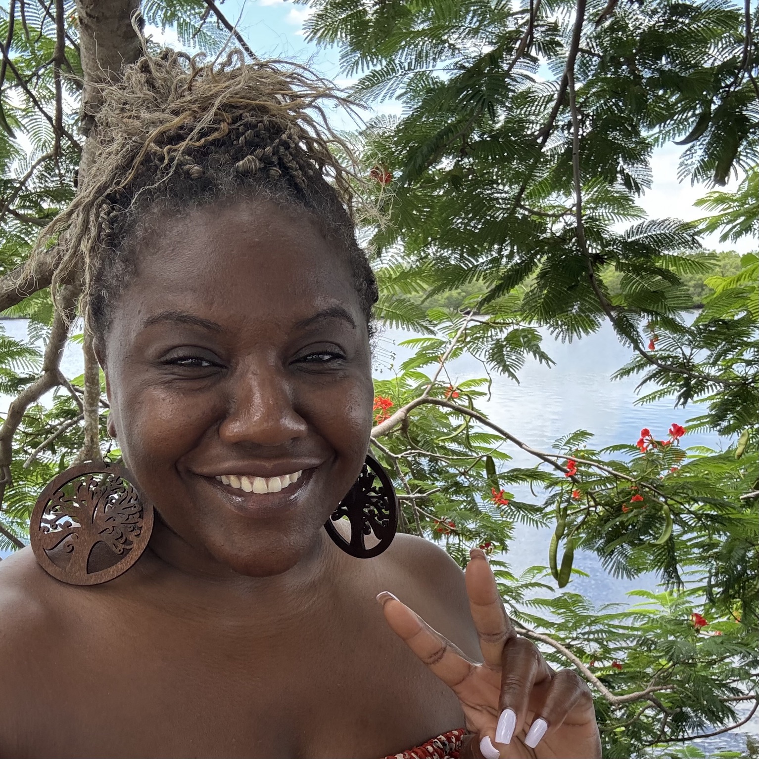 Rikkia smiling beneath flowering trees beside the water